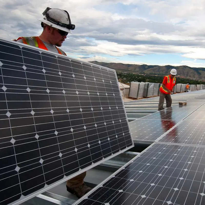 Técnicos com equipamento de segurança instalando painel solar
